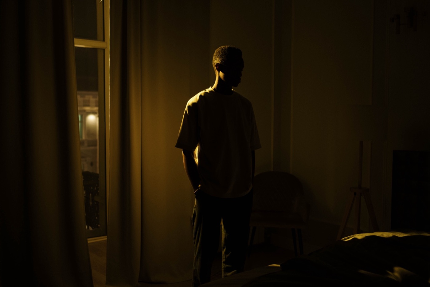 A man alone at night, the weight of unspoken things visible in his posture.